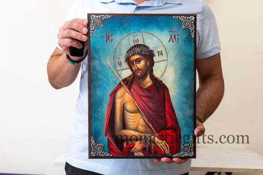 erson holding a religious icon of a bearded figure with a halo and cross.