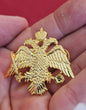 Large-scale handcrafted gold tone Orthodox double headed eagle crest lapel pin held on a hand for size reference