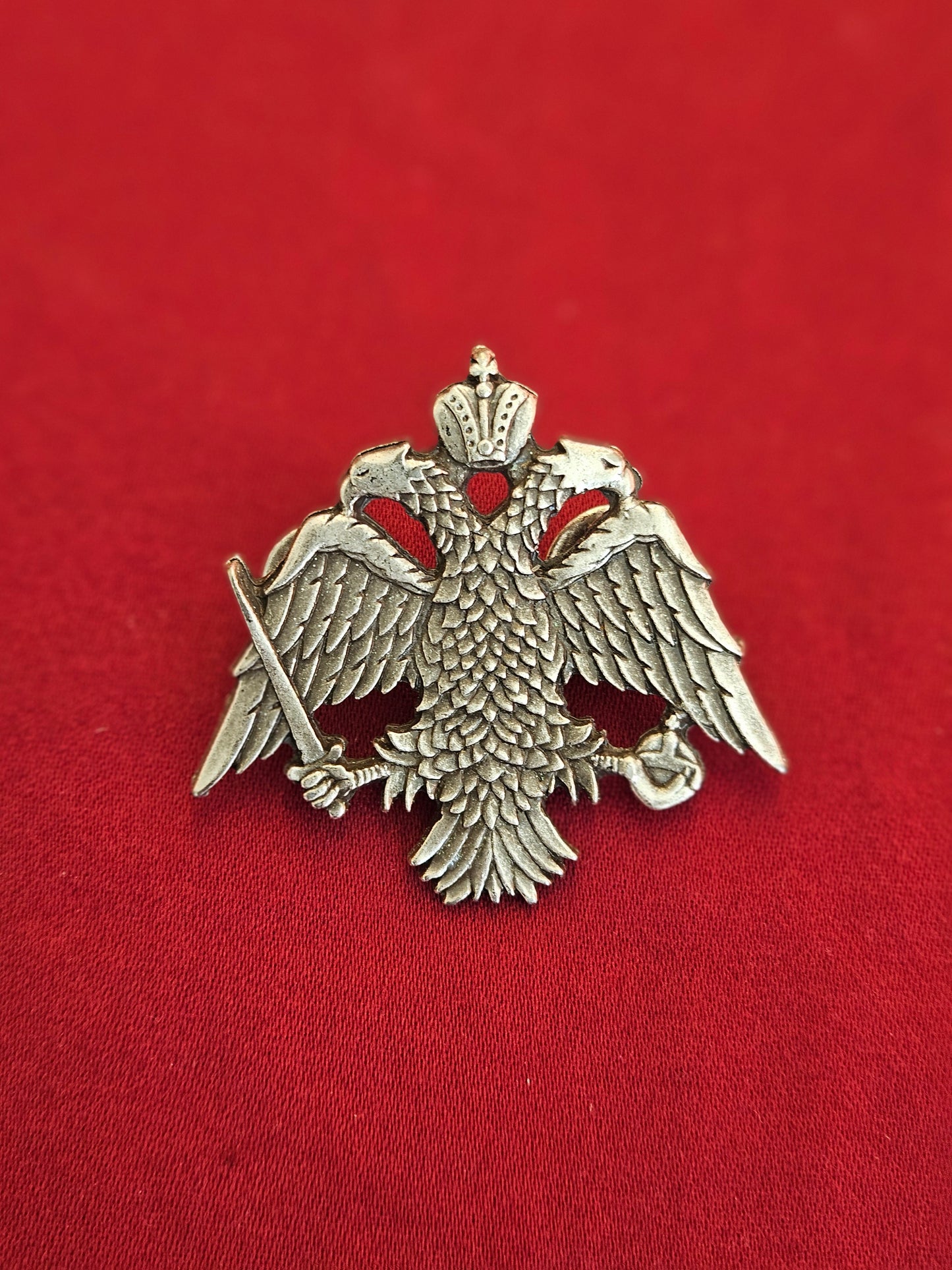 Large-scale handcrafted Orthodox double headed eagle crest lapel pin held on a hand for size reference
