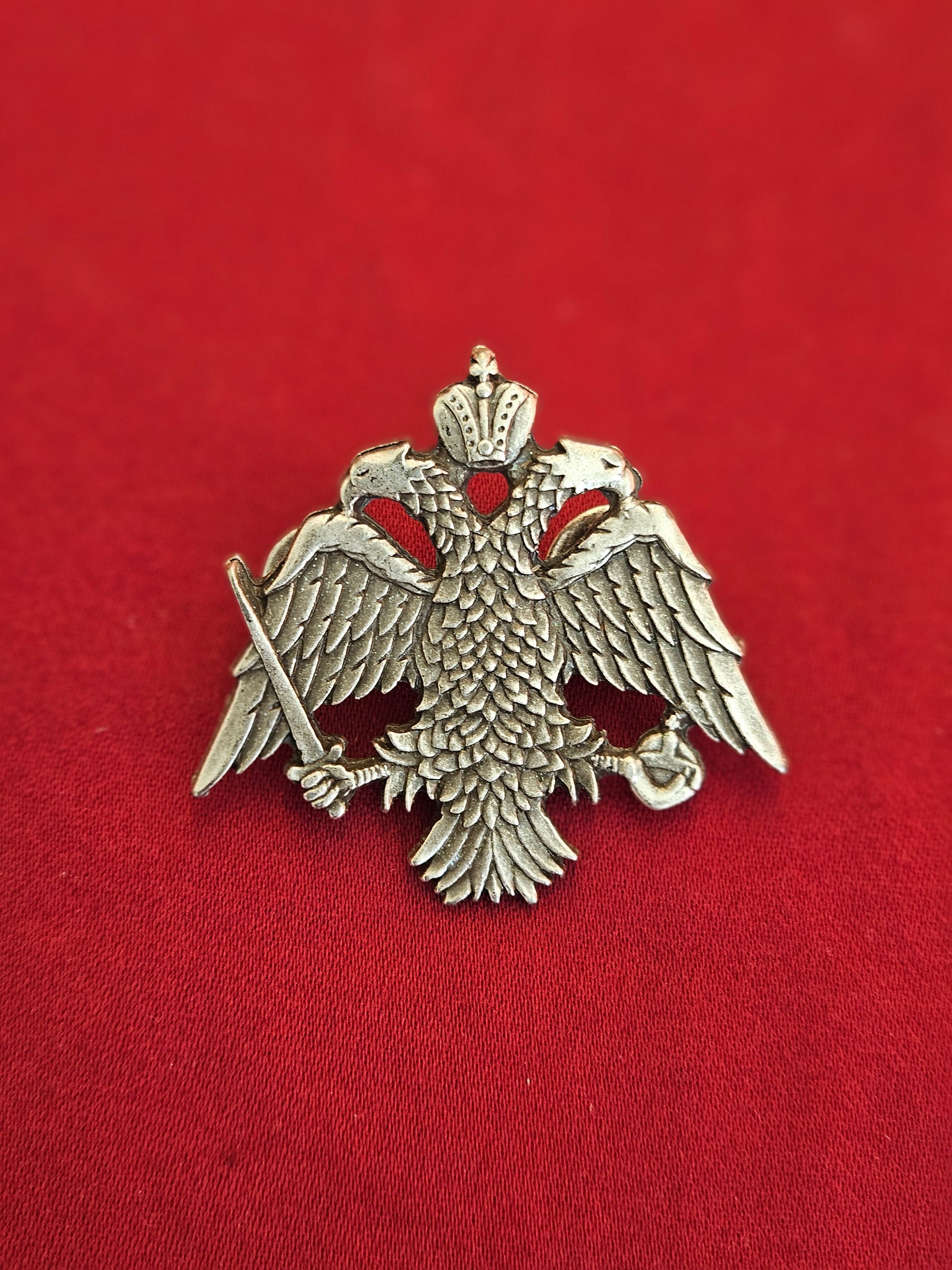 Large-scale handcrafted Orthodox double headed eagle crest lapel pin held on a hand for size reference