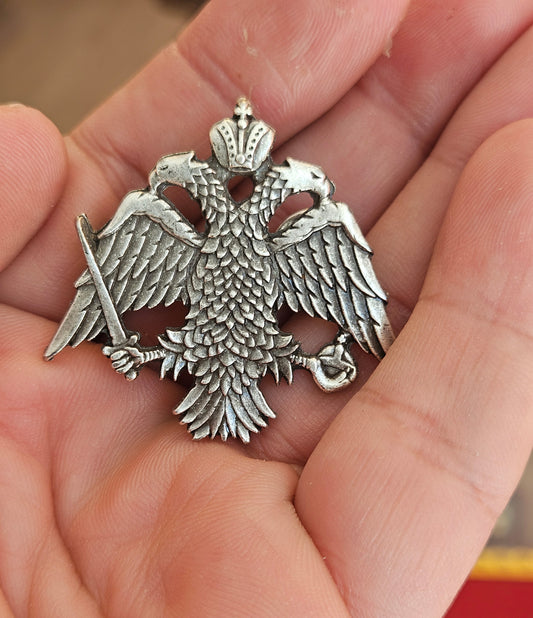 Large-scale handcrafted Orthodox double headed eagle crest lapel pin held on a hand for size reference