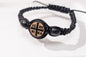 Ultra close-up view of the handcrafted black macrame Komboskini bracelet featuring an engraved round IC XC NIKA wooden cross