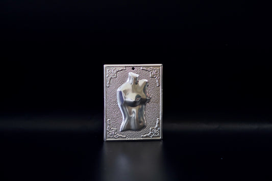 Plain silver-tone Greek Orthodox tama votive offering plaque embossed with a female torso motif and a small pre-drilled top hole for hanging.