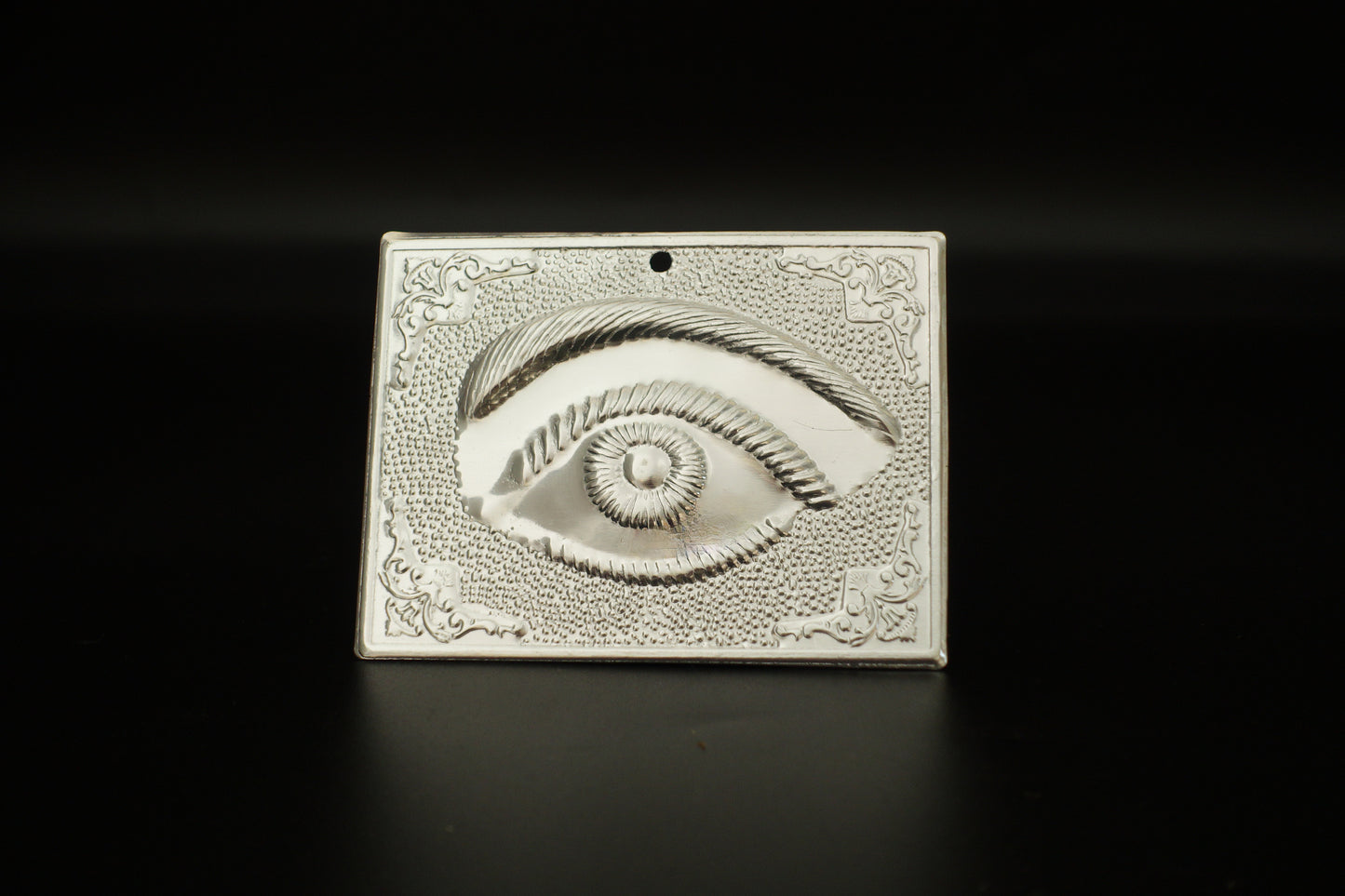 Plain silver-tone Greek Orthodox tama votive offering plaque embossed with a single eye motif and a small pre-drilled top hole for hanging.