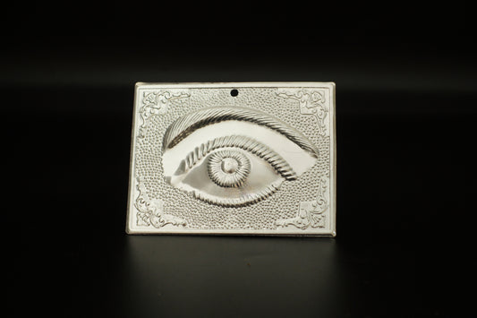 Plain silver-tone Greek Orthodox tama votive offering plaque embossed with a single eye motif and a small pre-drilled top hole for hanging.