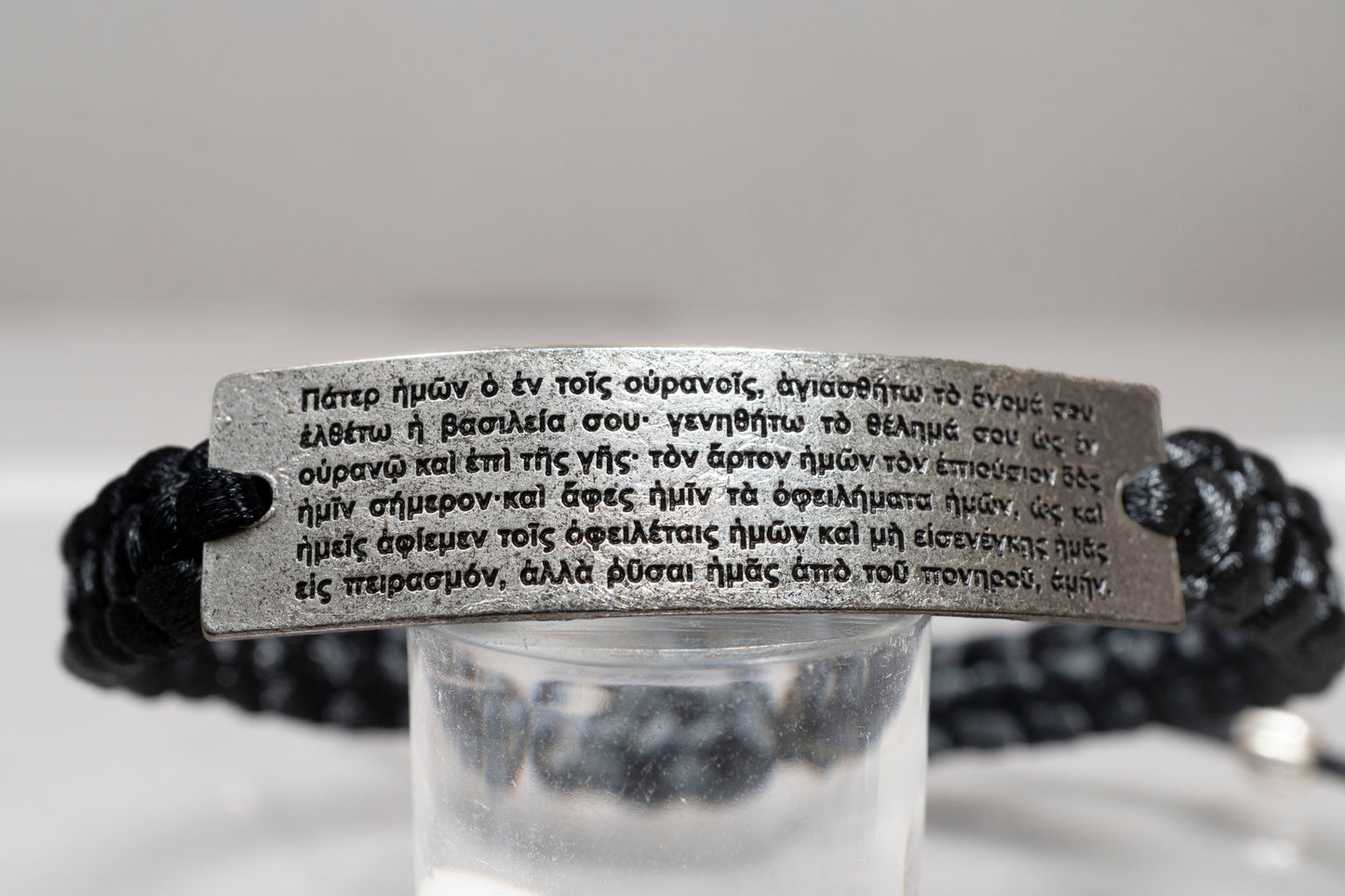 Detailed close up of the Lord's Prayer in Greek engraved on an antique silver plate macrame bracelet