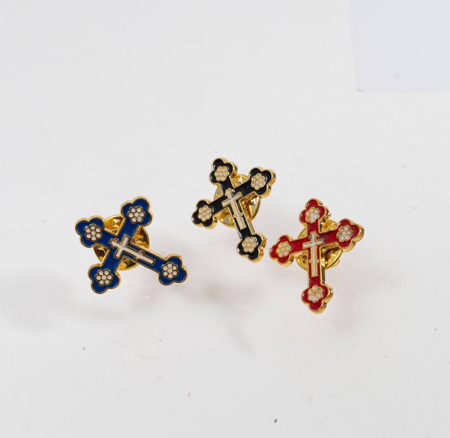 Rich red enamel Byzantine style cross lapel badge on a polished gold background