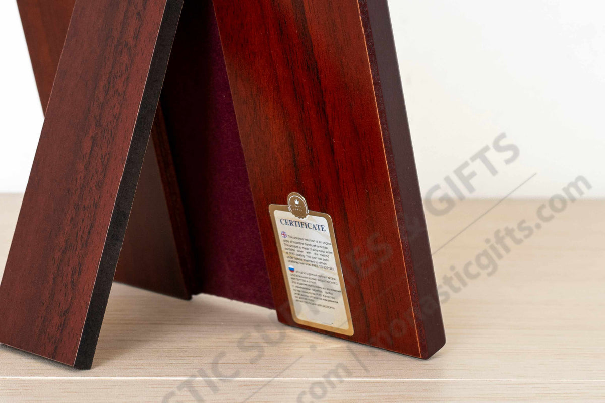 A close-up of a wooden display stand or easel made from polished reddish-brown wood planks, with a small certificate plaque attached to one side, standing on a light wood surface against a white background.