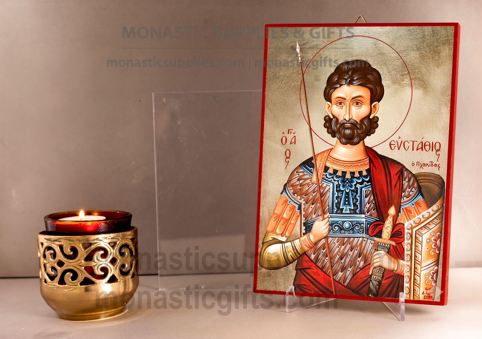 A Byzantine-style religious icon of Saint Eustathios on a clear acrylic stand, displayed next to a lit gold-toned candle holder against a neutral background.