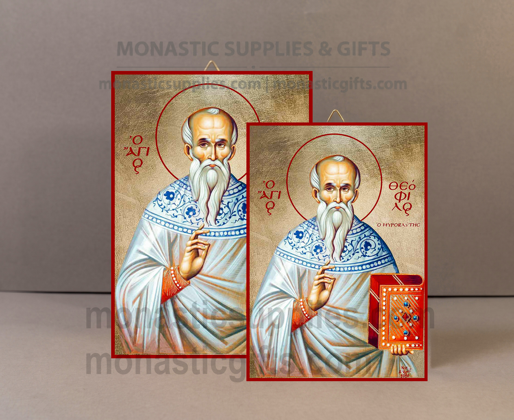 Two religious icons of Saint Paul showing him with a long white beard, wearing white and blue robes, displayed on a neutral gray background. One icon features a red hanging loop at the top, and the other includes a small red gift box at the bottom right.