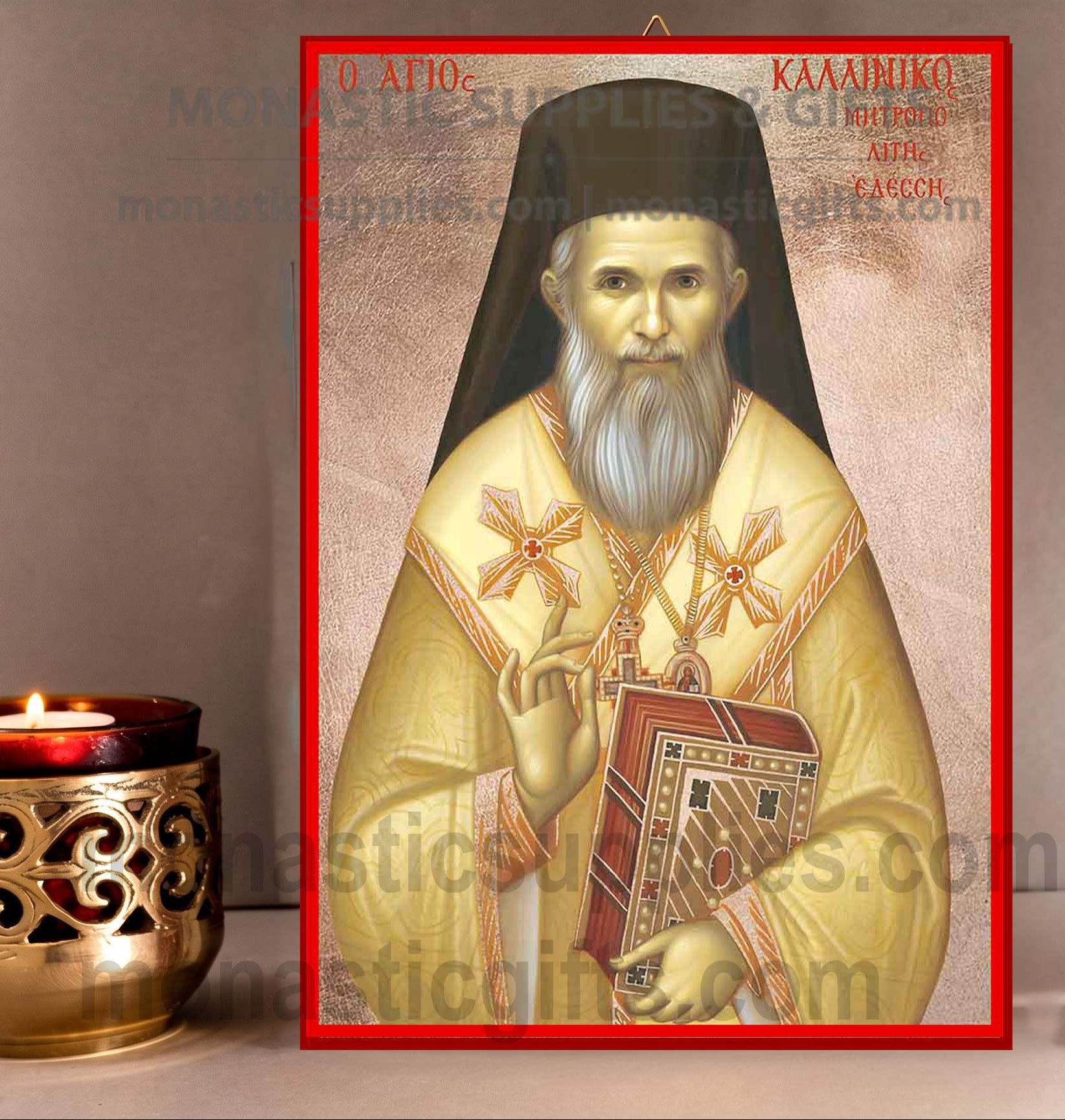 A framed religious icon of Saint Kallinikos showing him in gold vestments holding a book, displayed next to a lit brass candle holder on a neutral surface.